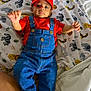animal_print, baby, bed, blanket, child, clothing, cute, denim, elephant, giraffe, indoors, infant, lion, mario, overalls, person, portrait, red_hat, smiling, zebra