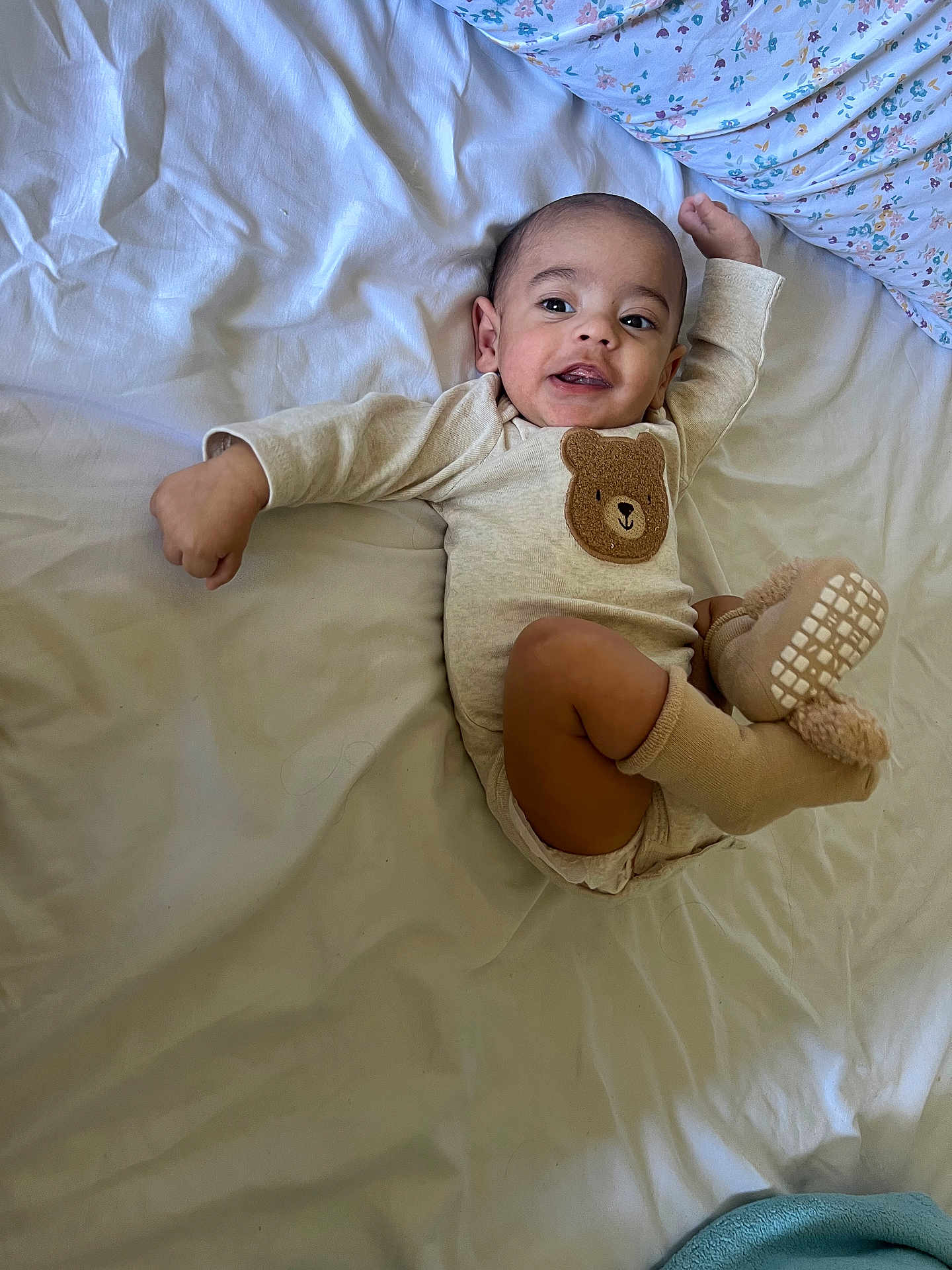 Máximo is registered to the contest to win money with this photo: baby, bed, blanket, clothing, cute, face, fuzzy_socks, happy, infant, laying_down, one_person, pajamas, plush, portrait, smiling, socks, toddler, toy_design, white_bed, young_child