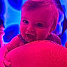 Sebastian is registered to the contest to win money with this photo: baby, child, smiling, face, arm, skin, tattoo, neon_lights, pink, blue, happy, portrait, infant, cute, closeup, person, colorful, lighting, indoor, expression