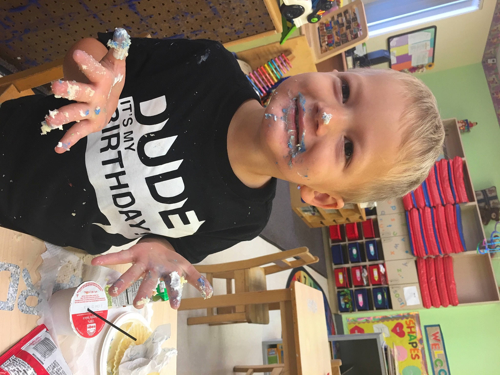 Richard is registered to the contest to win money with this photo: bookcase, child, drink, elbow, event, fun, happy, joy, person, play, room, shelf, sleeve, smile, t_shirt, toddler, top, wrist