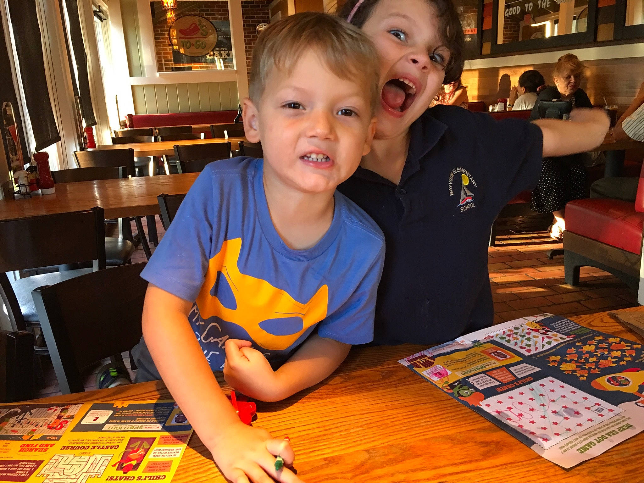 Richard is registered to the contest to win money with this photo: chair, child, desk, event, flooring, fun, happy, indoor_games_and_sports, leisure, person, play, recreation, room, sharing, sitting, smile, t_shirt, table, toddler, varnish