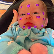 Skyler joined the competition — help win amazing prizes! baby, newborn, infant, face, emoji_filter, purple_emoji, onesie, mittens, pink_socks, parent_hand, hand, blanket, bedding, couch, boot, shoe, close_up, portrait, indoor, cute