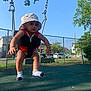 baby, casual_clothing, child, daylight, fence, fun, happy, hat, outdoor, park, playground, recreation, residential, sky, socks, summer, swing, toddler, trees, young_child