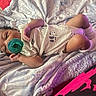 baby, infant, pacifier, blanket, onesie, panda_pattern, socks, lying_down, sleepy, cute, soft_texture, bed, resting, child, newborn, comfort, warm_lighting, purple_hue, indoor, cozy