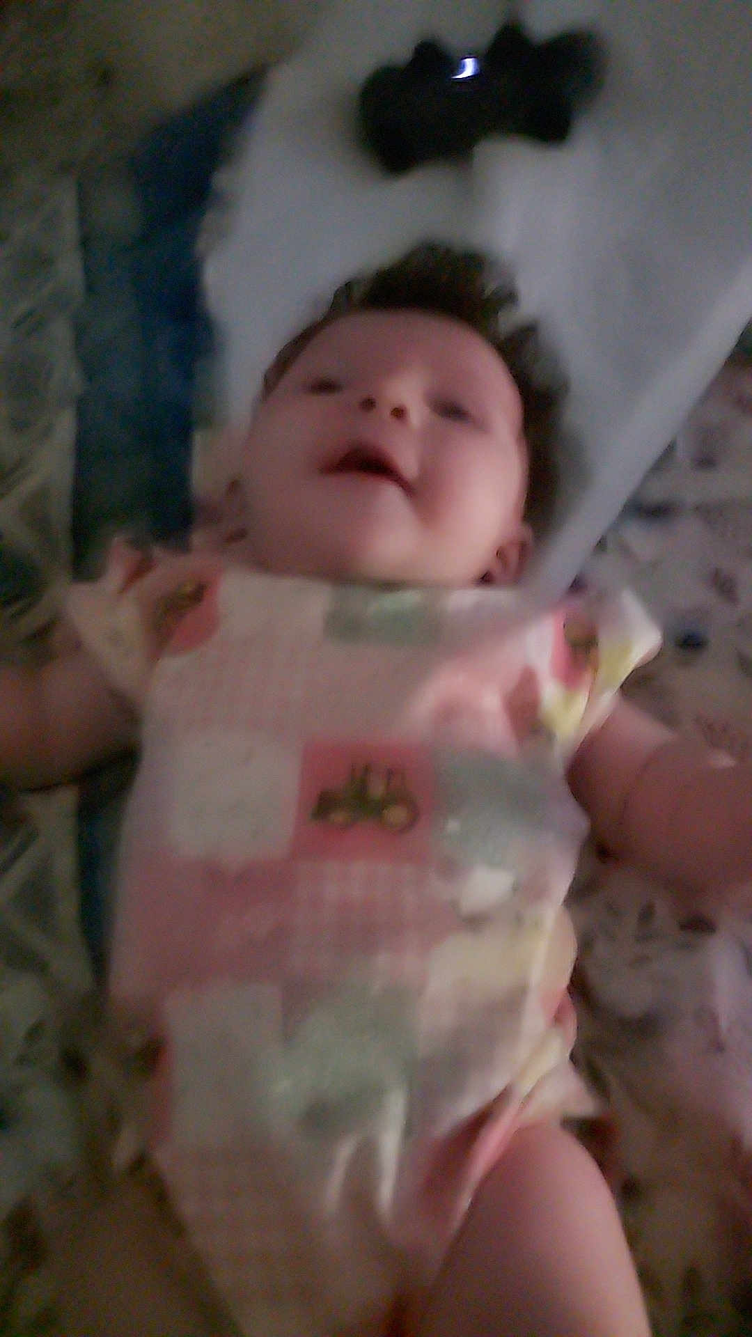Oaklynn is registered to the contest to win money with this photo: baby, infant, onesie, clothing, lying_down, face, child, smile, bed, bedding, pattern, soft, indoors, cute, happy, skin, person, young, blur, portrait