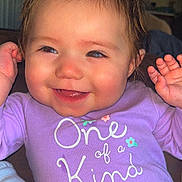 Ayla is registered to the contest to win money with this photo: baby, child, smiling, purple_shirt, hair_clip, indoor, cute, happy, person, portrait, toddler, clothing, face, hands, joy, infant, sitting, apparel, young_child, closeup