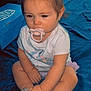 Ayla is registered to the contest to win money with this photo: baby, pacifier, unicorn, shirt, sandals, blue_blanket, sitting, child, indoor, cute, footwear, clothing, person, infant, soft_lighting, hair_tie, toy_box, expression, legs, hands