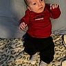 Ethan joined the competition — help win amazing prizes! baby, infant, child, portrait, lying_down, red_shirt, black_pants, striped_socks, blanket, bed, cushion, indoors, cozy, face, eyes, hands, fist, looking_at_camera, baby_clothing, dinosaur_theme