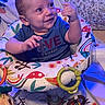 baby, child, smiling, blue_shirt, baby_seat, colorful, toy, playful, indoor, infant, happy, cute, face, person, sitting, clothing, patterned, soft_lighting, joyful, young