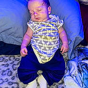 Ethan is registered to the contest to win money with this photo: baby, sleeping, onesie, pants, blanket, pillow, soft_texture, indoor, child, infant, cozy, rest, cute, peaceful, portrait, person, blue_light, feet, hand, lying_down