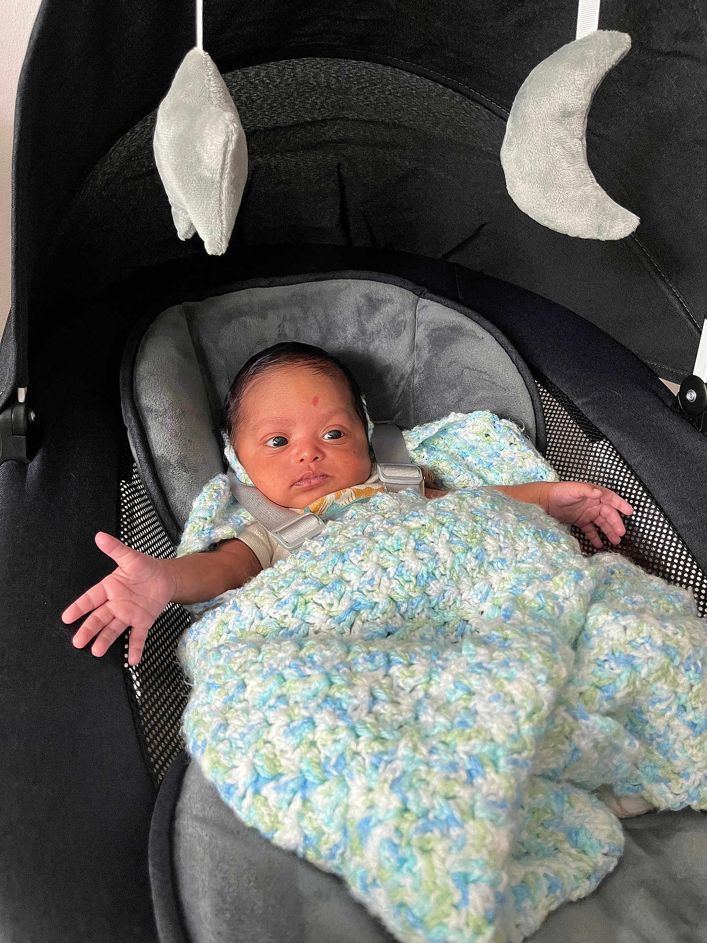 Jackson is registered to the contest to win money with this photo: baby, infant, car_seat, blanket, crocheted_blanket, plush_toy, moon_toy, star_toy, child, seatbelt, soft_toys, indoor, newborn, cute, wrapped, resting, small_hands, cozy, portrait, expression