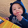 toddler, child, hoodie, navy_blue, bear_ears, table, striped, hand, face, expression, indoor, wall, texture, colorful, cute, person, young_child, snack, food, casual