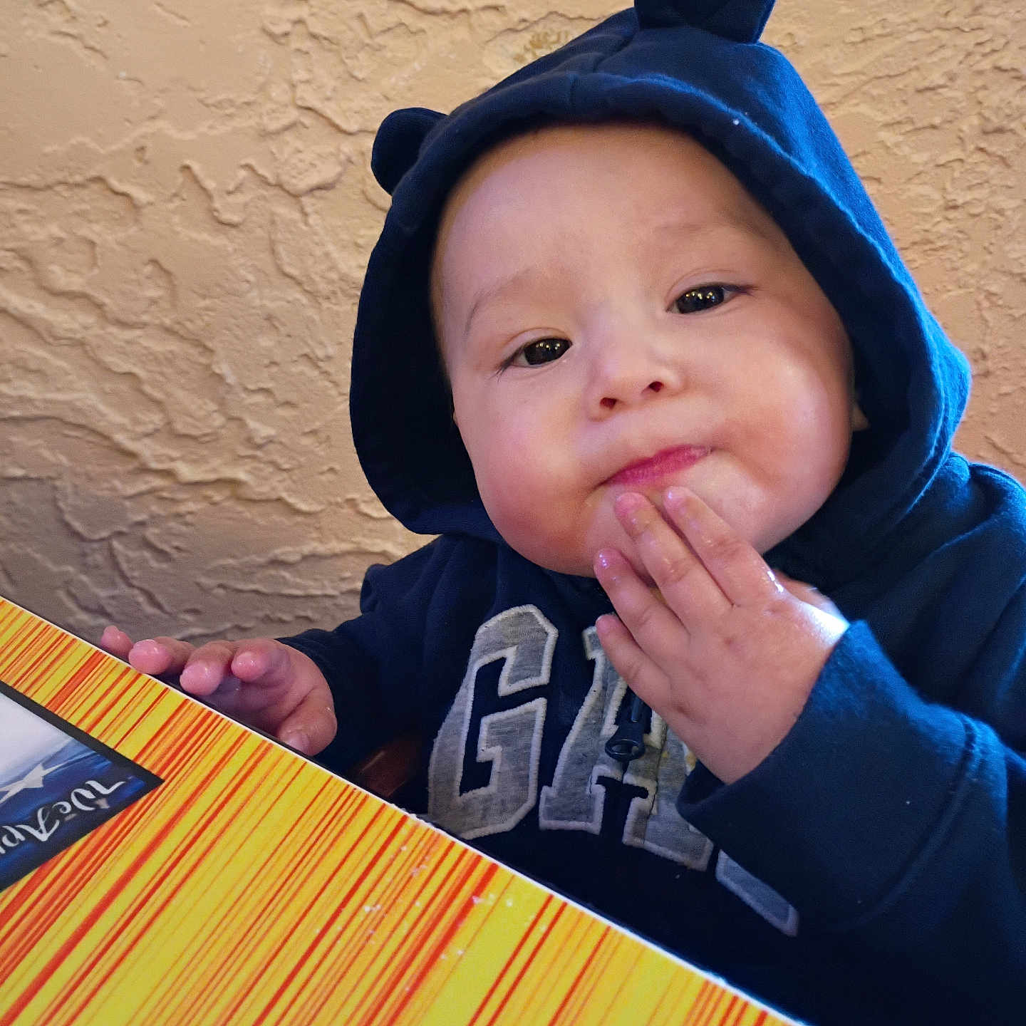 Josiah joined the competition — help win amazing prizes! toddler, child, hoodie, navy_blue, bear_ears, table, striped, hand, face, expression, indoor, wall, texture, colorful, cute, person, young_child, snack, food, casual