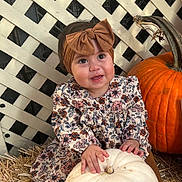 Citlali joined the competition — help win amazing prizes! baby, child, pumpkin, white_pumpkin, orange_pumpkin, bow_headband, floral_dress, straw, lattice_fence, fall, autumn, cute, smiling, sitting, outdoor, person, headband, baby_shoes, brown_shoes, seasonal