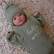 Huxley is registered to the contest to win money with this photo: baby, infant, knitted_hat, knitted_outfit, green_clothing, blanket, soft_texture, cute, newborn, lying_down, face, expression, cozy, warm, indoor, small_hands, portrait, child, baby_wear, closeup