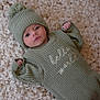 baby, infant, knitted_hat, knitted_outfit, green_clothing, blanket, soft_texture, cute, newborn, lying_down, face, expression, cozy, warm, indoor, small_hands, portrait, child, baby_wear, closeup