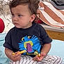 Marcel a rejoint le concours — aidez-le/la à gagner de superbes lots ! toddler, child, fries, blue_eyes, curly_hair, striped_pants, black_tshirt, beach_towel, sand, outdoor, sitting, food, casual_clothing, summer, relaxed, portrait, daytime, snack, serious_expression, barefoot