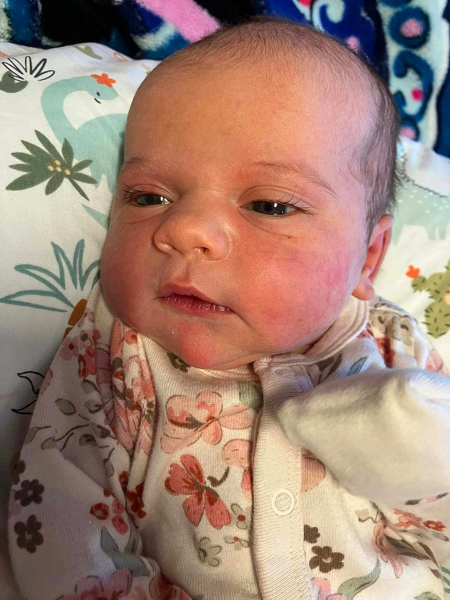 Everleigh Ann Canter joined the competition — help win amazing prizes! baby, infant, face, person, clothing, floral_pattern, onesie, blanket, soft_lighting, closeup, skin, head, eyelashes, cheeks, newborn, sleepwear, cute, indoors, resting, portrait