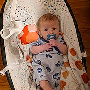 Atlas joined the competition — help win amazing prizes! baby, pacifier, blanket, baby_rocker, toy, floor, wood_floor, clothing, infant, child, person, cute, indoors, comfort, resting, playful, blue, orange, patterned, soft