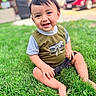 toddler, child, smiling, happy, portrait, outdoor, grass, lawn, sitting, dinosaur_shirt, shorts, face, eyes, hair, parked_car, red_car, daylight, greenery, photography, playful