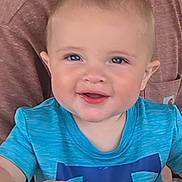 Kyrie is registered to the contest to win money with this photo: baby, child, smiling, blue_shirt, face, eyes, happy, portrait, infant, cute, person, skin, head, background, seated, clothing, indoors, expression, young_child, cheerful