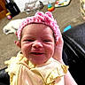 baby, newborn, smile, pink_headband, yellow_outfit, bee_pattern, hand_holding, indoor, carpet, toy, cat, furniture, cabinet, child, portrait, cute, happy, infant, face, person