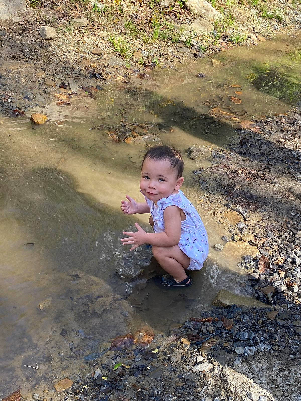 Phoenix joined the competition — help win amazing prizes! asphalt, baby, baby_toddler_clothing, body_of_water, child, fun, geology, grass, joy, landscape, leisure, mud, people_in_nature, person, plant, puddle, road_surface, rock, sand, sitting