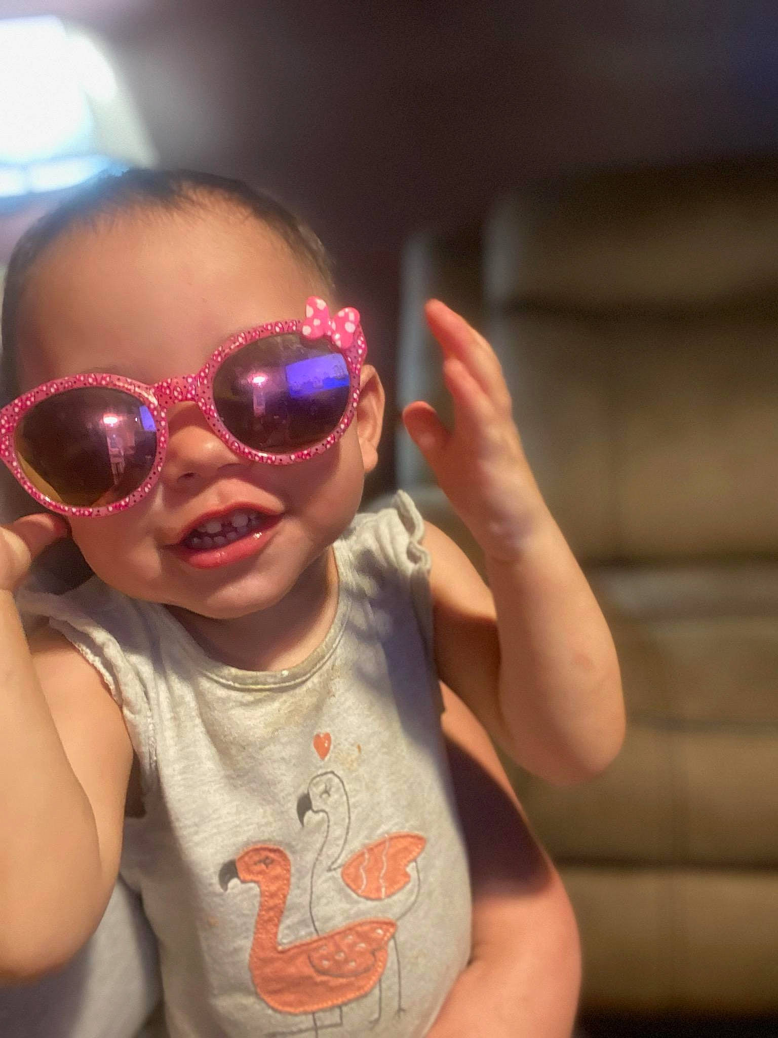 Phoenix is registered to the contest to win money with this photo: baby_toddler_clothing, cheek, eyewear, finger, gesture, glasses, goggles, hand, happy, lip, mouth, nose, person, personal_protective_equipment, pink, skin, smile, sunglasses, thumb, toddler