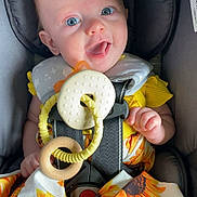 Olivia joined the competition — help win amazing prizes! baby, child, smiling, car_seat, blue_eyes, sunflower_pattern, yellow_clothing, teething_toy, infant, cute, happy, seat_belt, fabric, indoor, closeup, young_child, playful, comfort, portrait, person