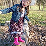 Olivia joined the competition — help win amazing prizes! child, girl, smiling, hat, glasses, denim_jacket, dress, rain_boots, log, outdoor, nature, trees, grass, leaves, sunlight, balance, playful, park, fall, happy