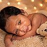 baby, infant, teddy_bear, blanket, soft_texture, cozy, portrait, closeup, warm_lighting, fairy_lights, cute, sleepy, resting, knitted_toy, child, indoor, comfort, peaceful, fuzzy, newborn