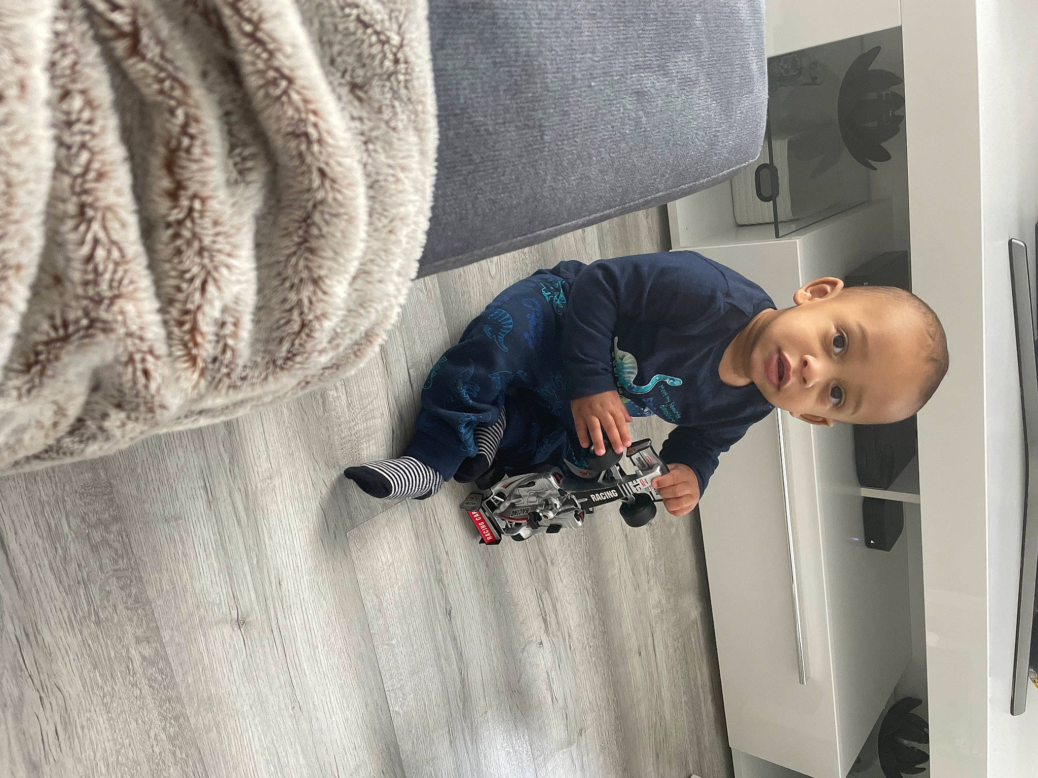 Cameron a rejoint le concours — aidez-le/la à gagner de superbes lots ! auto_part, automotive_tire, comfort, couch, floor, flooring, grey, hardwood, linens, outerwear, pattern, person, room, sitting, sleeve, smile, t_shirt, toddler, tree, vehicle_door