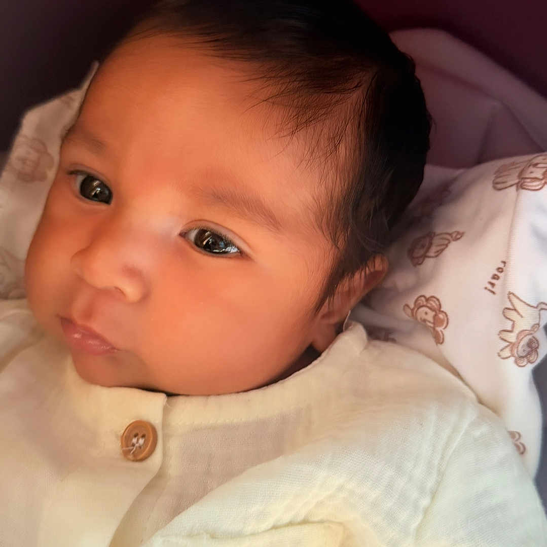 Chadwick joined the competition — help win amazing prizes! baby, infant, child, portrait, face, eyes, looking, awake, onesie, clothing, white_outfit, bee_design, smiling, cozy, blanket, crib, indoor, close_up, head, safe