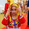 Leyna participe au concours pour gagner de l'argent avec cette photo : child, traditional_clothing, colorful, headwear, red_carpet, festival, celebration, person, portrait, cultural, indoors, people, dress, patterned, event, young, female, smile, hand, background
