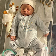 éthan a rejoint le concours — aidez-le/la à gagner de superbes lots ! baby, newborn, sleeping, crib, hat, onesie, plush_toy, giraffe_toy, soft_toy, blanket, footwear, infant, cute, peaceful, child, nursery, cozy, sleep, clothing, indoor