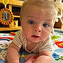 baby, infant, blue_eyes, play_mat, toddler, curious, indoors, soft_lighting, face, hands, clothing, striped_shirt, colorful, toy, mirror, wooden_furniture, closeup, child, cute, expression