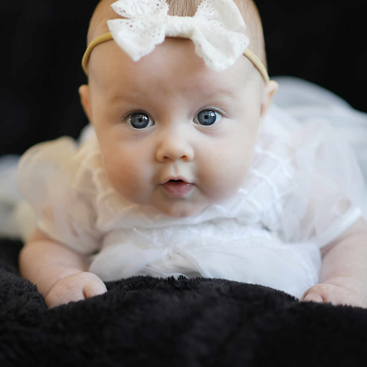 Quincey joined the competition — help win amazing prizes! baby, infant, face, headband, white_bow, blue_eyes, soft_blanket, black_background, cute, portrait, newborn, clothing, lying_down, closeup, child, adorable, soft_lighting, baby_girl, toddler, expression