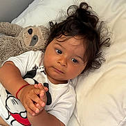 Joshua participe au concours pour gagner de l'argent avec cette photo : baby, child, curly_hair, mickey_mouse, tshirt, red_bracelet, plush_toy, sloth, pillow, blanket, bed, hands, clasped_hands, indoor, cute, portrait, closeup, sleeping_area, soft_toys, resting