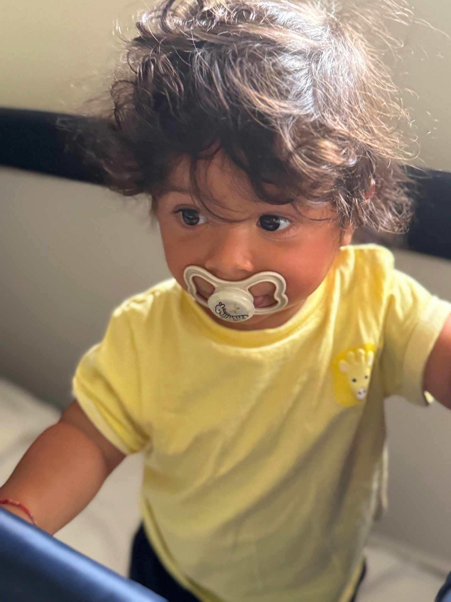 Joshua a rejoint le concours — aidez-le/la à gagner de superbes lots ! toddler, child, pacifier, yellow_shirt, curly_hair, indoors, portrait, cute, giraffe_patch, baby, expression, face, person, young_child, soft_light, casual_clothing, closeup, innocent, looking_away, curiosity