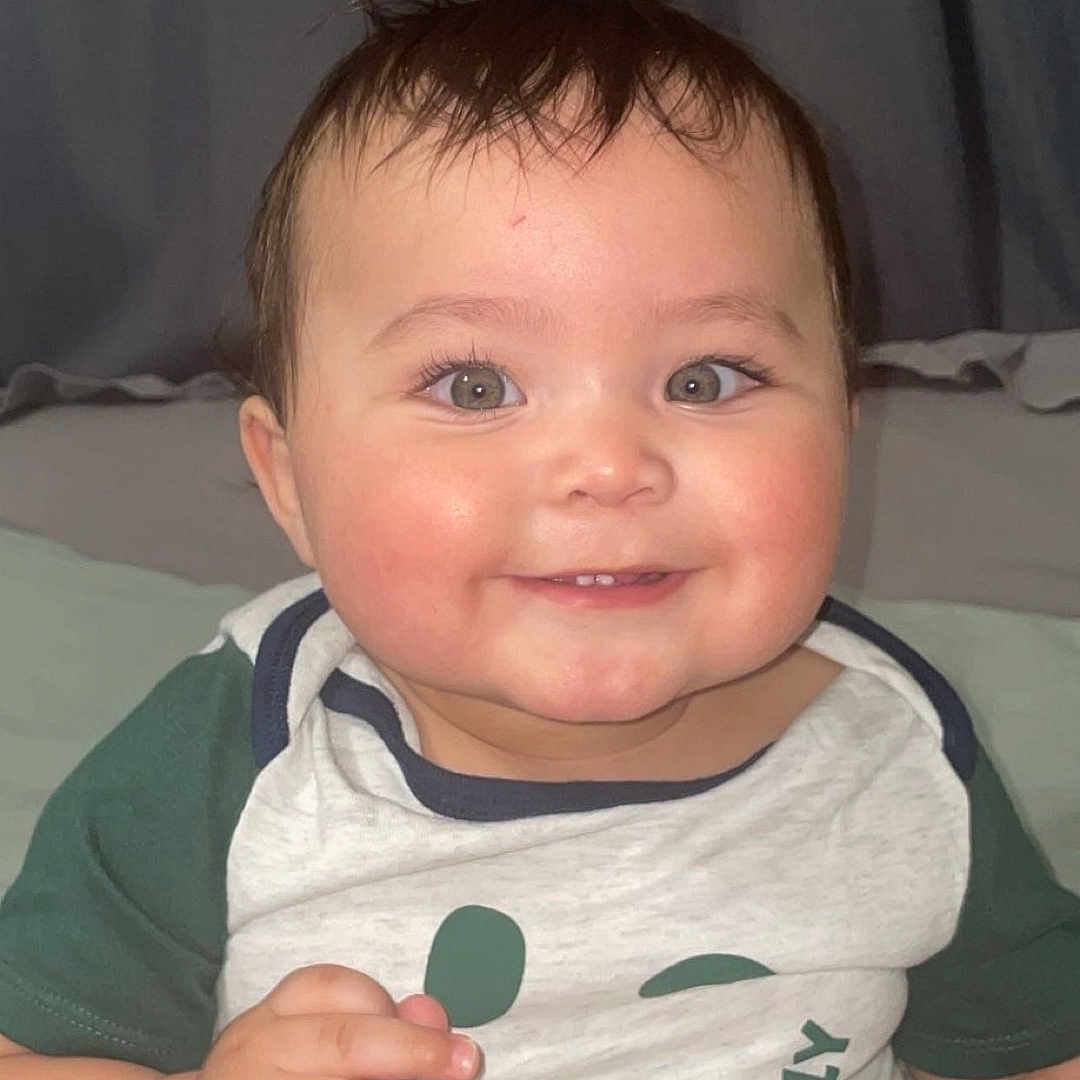 Santiago joined the competition — help win amazing prizes! baby, cheeks, child, clothing, cute, eyes, face, hair, hand, happy, indoor, infant, onesie, person, portrait, sitting, skin, smiling, toddler, vibes_only