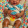 animal_print, baby, baby_seat, child, clothing, colorful, cute, face, hands, happy, indoors, infant, legs, patterned, person, skin, smiling, socks, sun_pattern, young