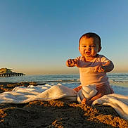 Isla joined the competition — help win amazing prizes! baby, beach, clothing, cute, horizon, infant, ocean, pier, portrait, sand, seashore, sitting, sky, smile, sunlight, sunset, toddler, towel, water, waves
