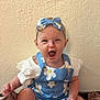 baby, infant, child, blue_romper, headband, flower_pattern, carpet, wall, sign, eight_months, smiling, sitting, clothing, cute, indoors, person, happy, skin, hand, foot