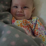 Paisleigh is registered to the contest to win money with this photo: baby, infant, blanket, polka_dots, floral_clothing, smile, face, head, cozy, cute, child, portrait, indoors, soft_lighting, colorful, warm, comfort, young, happy, person