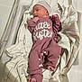 newborn, baby, hospital, bassinet, blanket, onesie, hat, footprints, infant, person, sleepwear, striped, text, lying_down, hospital_bed, cute, small, child, wrapped, mauve