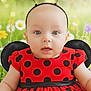 baby, child, costume, ladybug, red_dress, polka_dots, headband, antennae, portrait, cute, smiling, outdoor, flowers, greenery, infant, happy, closeup, face, eyes, skin