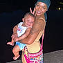Kane joined the competition — help win amazing prizes! woman, baby, child, smiling, peace_sign, tattoo, headscarf, night, outdoor, colorful_bag, holding, happy, portrait, person, skin, clothing, cute, peace, fun, toddler