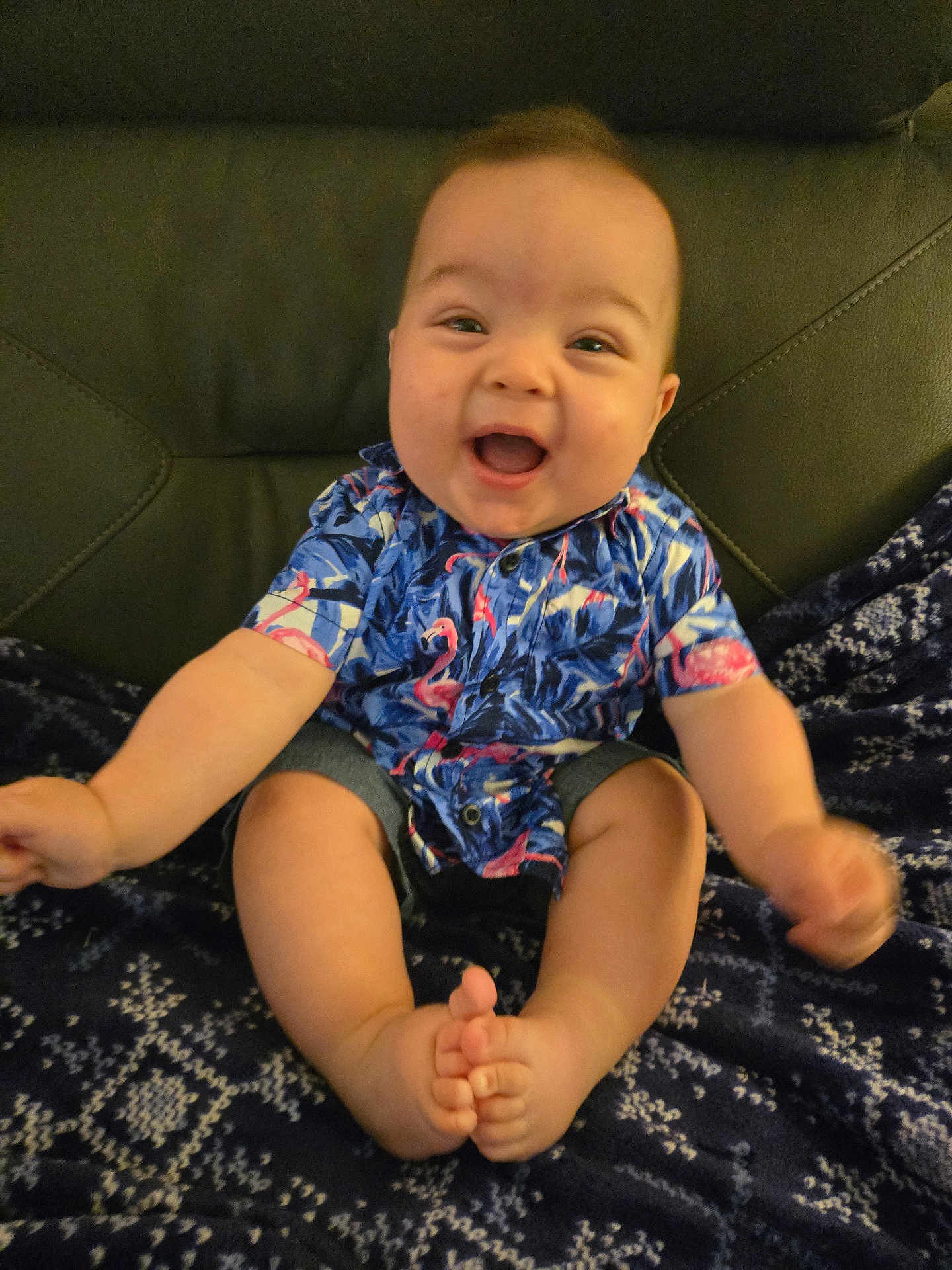 Thorne joined the competition — help win amazing prizes! baby, child, smiling, happy, sitting, shirt, flamingo, patterned_blanket, denim_shorts, feet, toes, indoor, furniture, couch, cute, portrait, infant, person, clothing, skin
