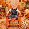 autumn, baby, bare_feet, child, fall, harvest, indoor, infant, leaves, nine_months, orange_chair, overalls, portrait, pumpkins, rocking_chair, seasonal_decor, sitting, smiling, studio_photo, white_shirt