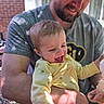Leighton is registered to the contest to win money with this photo: adult, affection, baby, beard, casual_clothing, child, daylight, expression, face, happy, holding, human, joy, man, onesie, outdoor, parent, portrait, smiling, yellow_clothing
